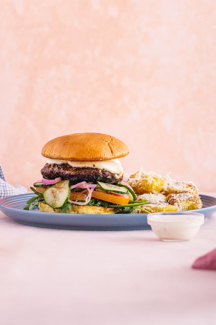 Trøffelburger med mozzarella, smashede krydderpoteter, sylteagurk, ruccola og tomat