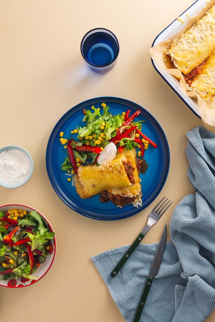 Gratinerte burritoer fylt med ferdiglaget chili con carne, med salat og rømme