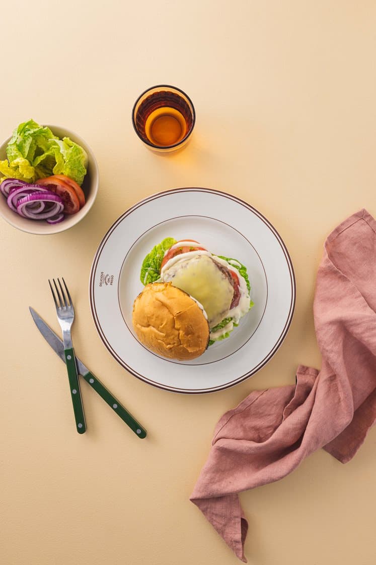 Saftig burger i briochebrød med ost, aioli, frisk salat og tomatskiver 