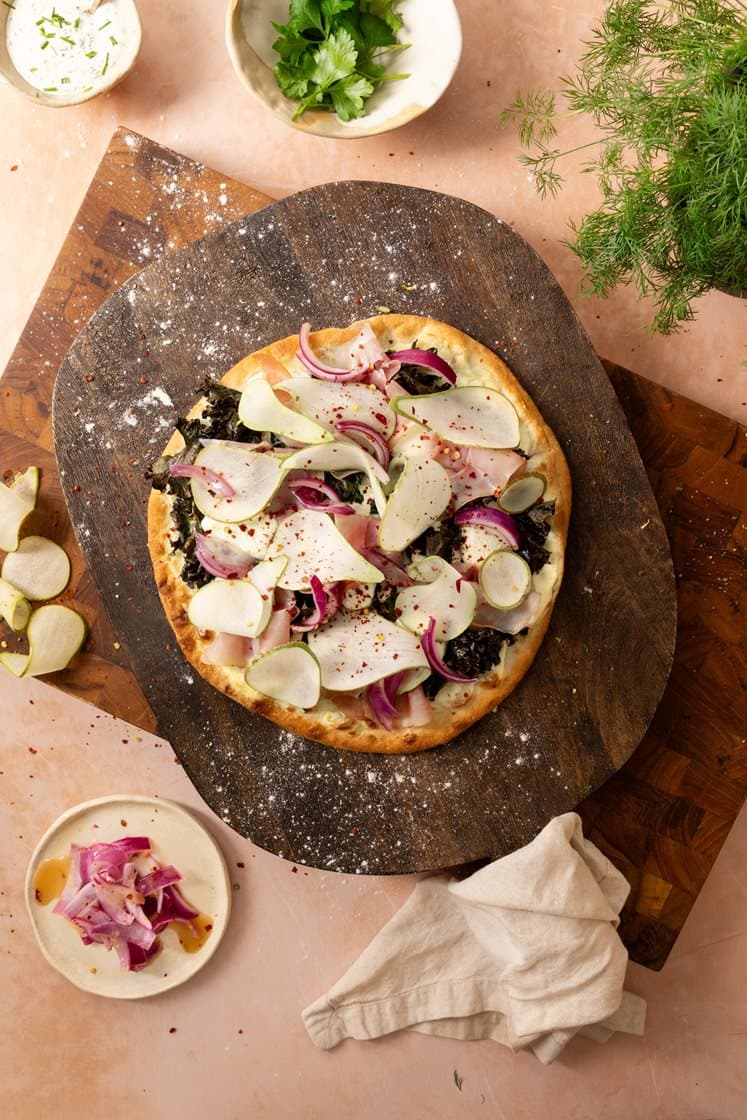 Pizza Bianca med honningglasert løk, chevre og grønnkål, toppet med spekeskinke og pære