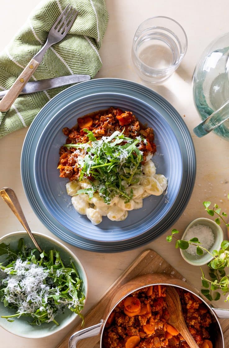 Tomatgryte med storfe-, linse- og svinedeig, kremet gnocchi og revet ost