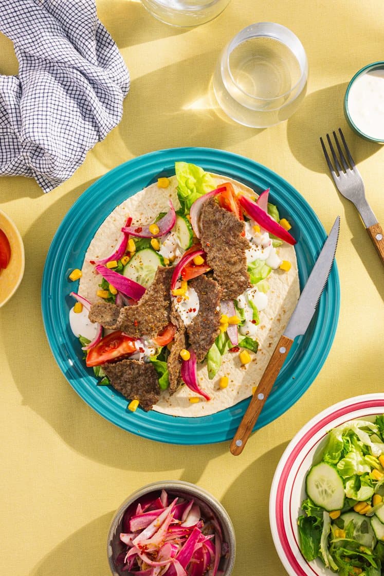 Svinekebab i tortillalefse med friske grønnsaker, urtedressing og sylta rødløk