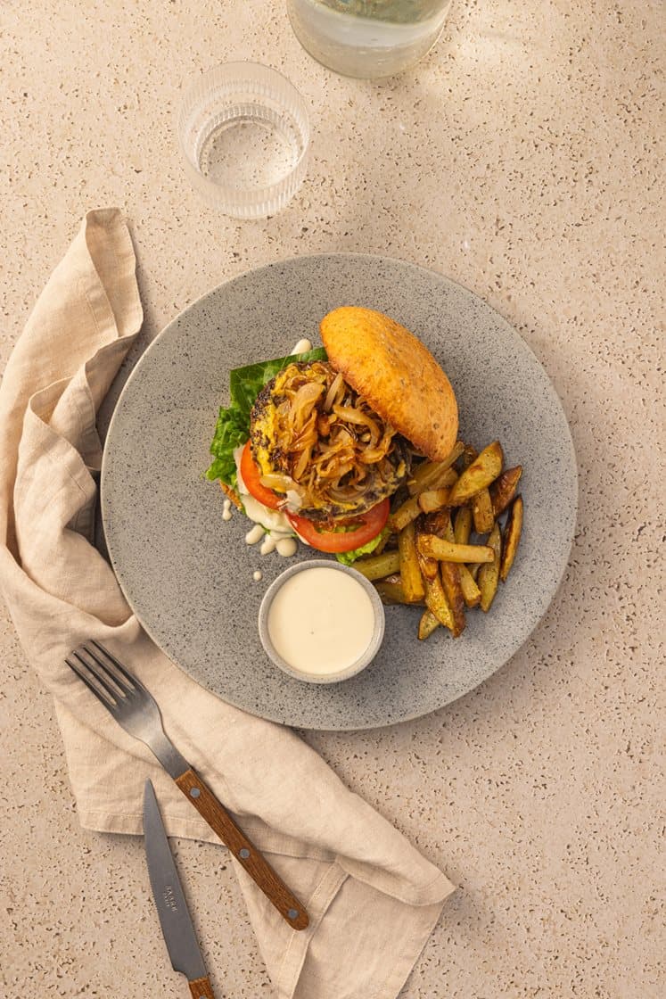 Klassisk burger med karamellisert løk og dijonsennep, tomatsalat i cæsardressing og urtefries