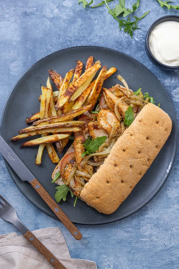 Kyllingsandwich med stekt løk, tomat og ruccola, servert med trøffelaioli og potetfries
