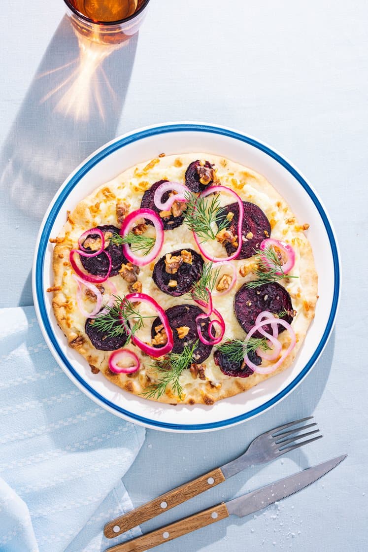Hvit pizza med rødbeteskiver, valnøtter, syltet rødløk og dill