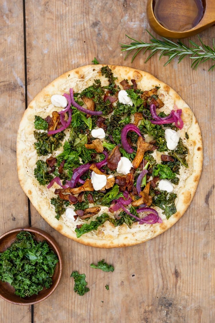 Pizza med hvit saus, bacon og smørstekte kantareller, toppet med syltet rødløk