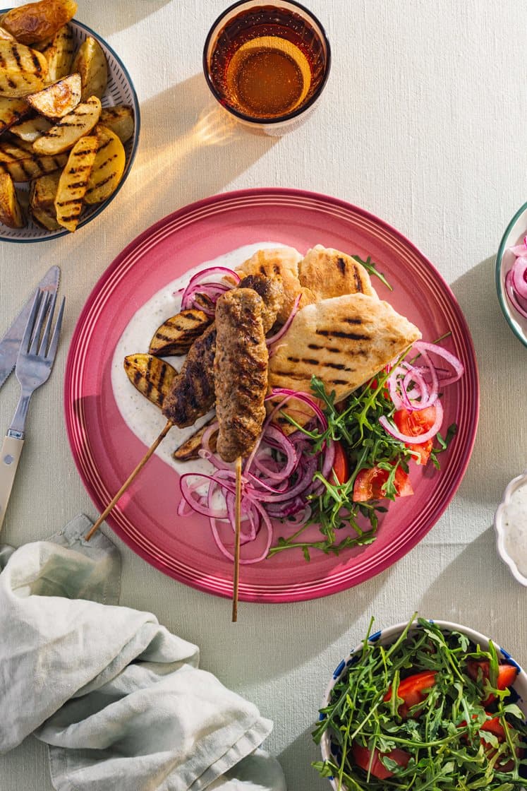 Grillet adana-kebab med potetbåter, råmarinert løk, yoghurtdressing og varme brød