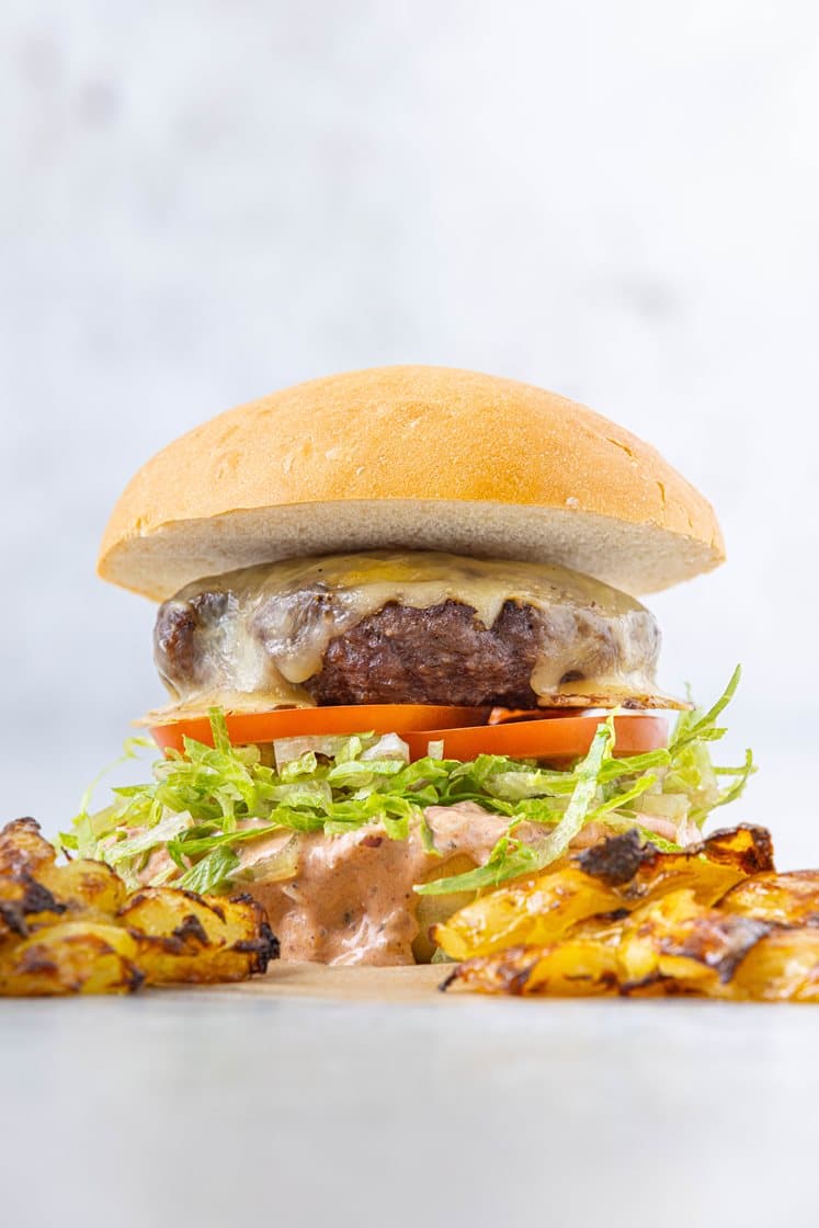 Klassisk cheeseburger servert med smashede poteter