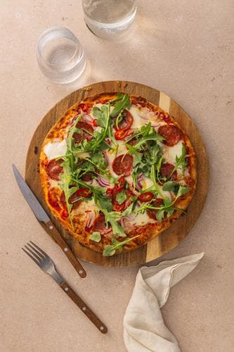Pizza Diavola med mozzarella, pepperoni, rødløk og chili, servert med ruccola