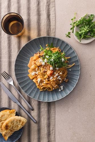 Kremet pasta med bakte grønnsaker, servert med fetaost og varme brød