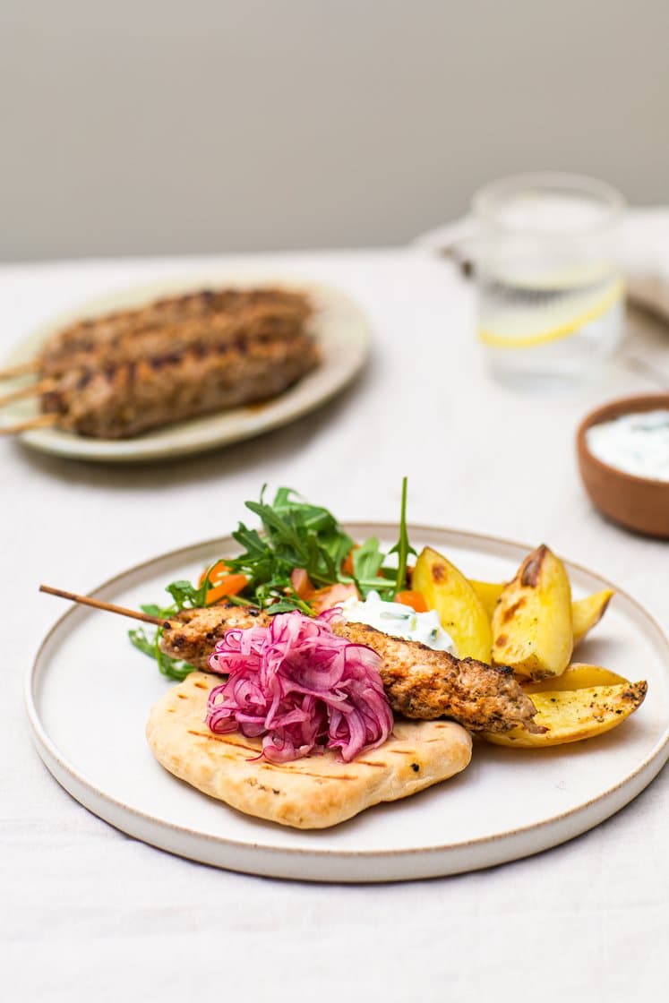 Adana-kebab med potetbåter, råmarinert løk, yoghurtdressing og varme brød