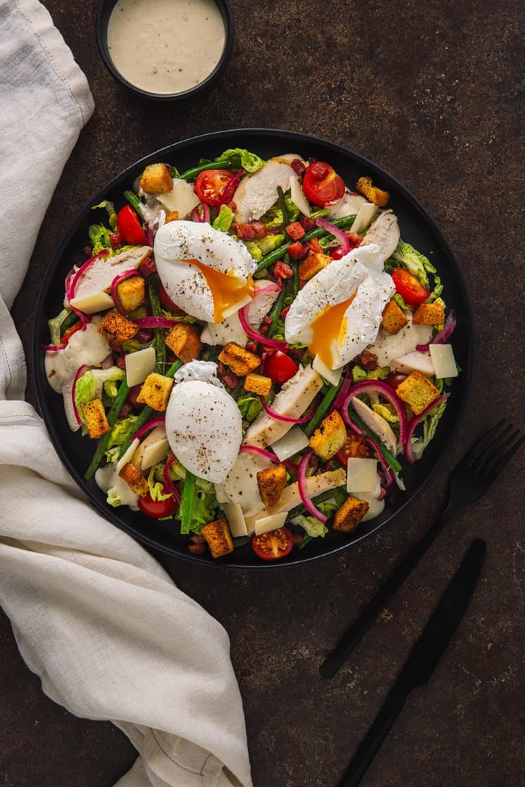Cæsarsalat med kylling og bacon, servert med brioche-krutonger, aspargesbønner og posjert egg