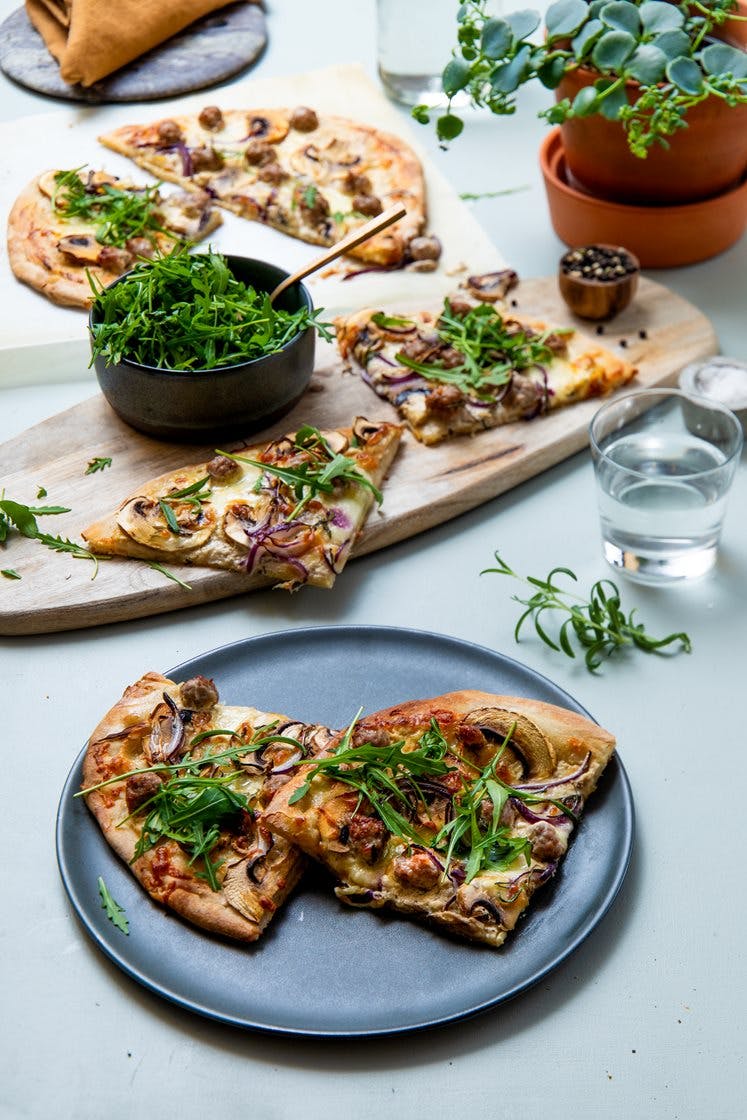 Hvit pizza med salsicciaboller toppet med aromasopp og urter