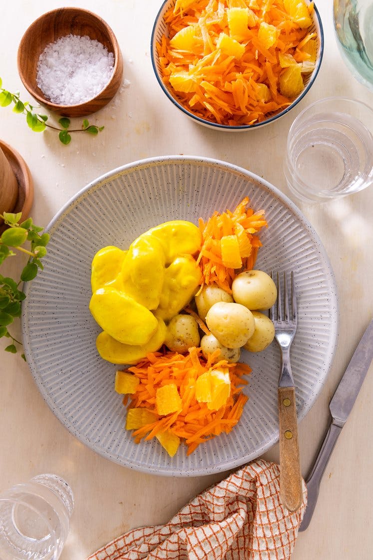 Fiskeboller i karrisaus med poteter og revne gulrøtter med appelsin