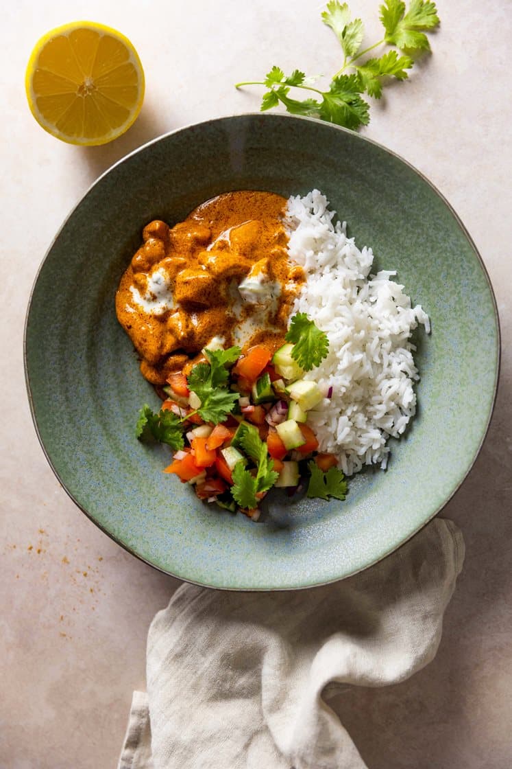 Indisk butter chicken med ris og kachumbersalat, servert med krydret yoghurt