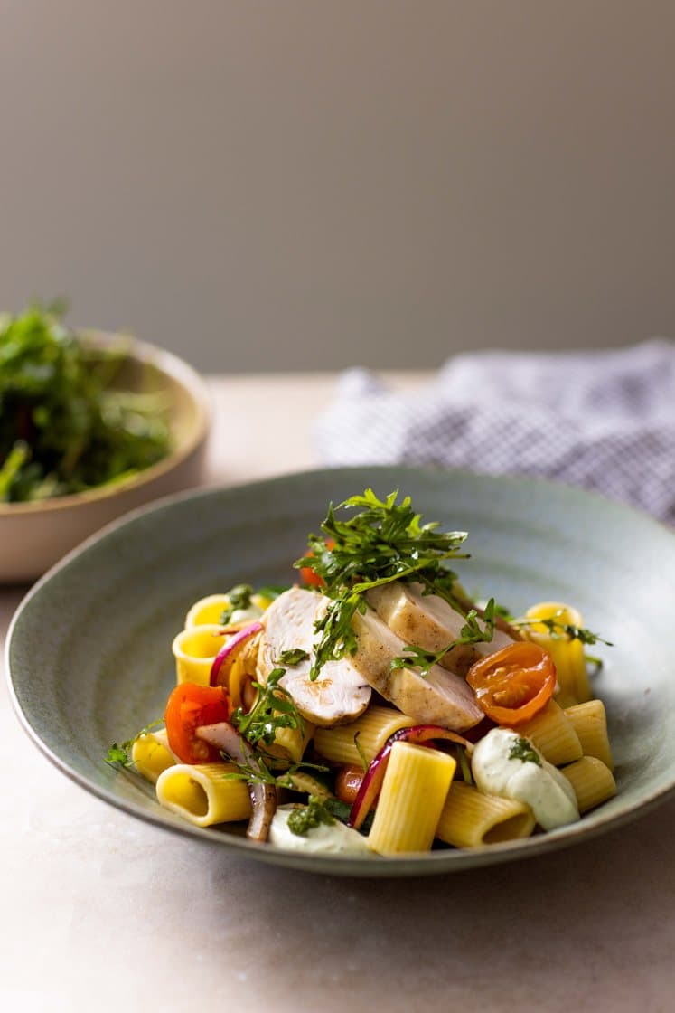 Ovnsbakt kyllingbryst og cherrytomater servert med pasta, pestokrem og ruccolasalat